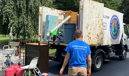 Professional Superman Junk and Moving movers carefully carrying furniture and boxes from a home.